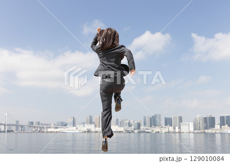 都会をスーツ姿でジャンプするキャリアウーマン 129010084