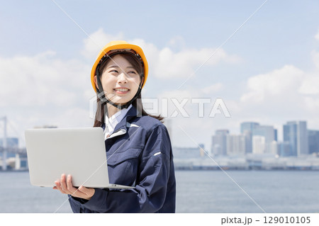 ノートパソコンを使う作業服を着た若い女性 ノートパソコンを使う作業服を着た若い女性 129010105