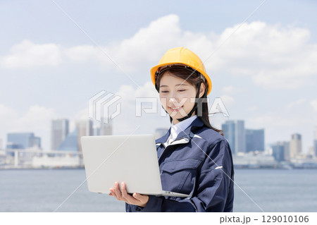 ノートパソコンを使う作業服を着た若い女性 ノートパソコンを使う作業服を着た若い女性 129010106