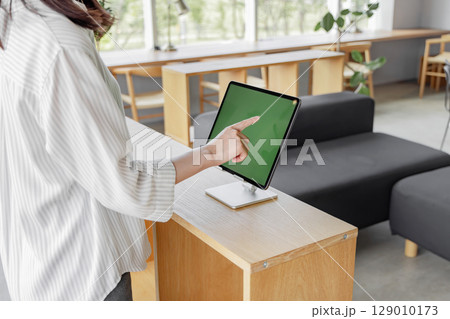 ホテルで受付をする若い女性　タブレット　セルフチェックイン 129010173