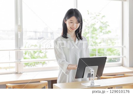 ホテルで受付をする若い女性　タブレット　セルフチェックイン 129010176