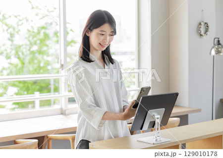 ホテルで受付をする若い女性 タブレット セルフチェックイン ホテルで受付をする若い女性 タブレット セルフチェックイン 129010178