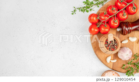 Fresh cherry tomatoes on the vine with garlic, peppercorns, herbs, and pink salt on a wooden board. copy space, top view Fresh cherry tomatoes on the vine with garlic, peppercorns, herbs, and pink salt on a wooden board. copy space, top view 129010454