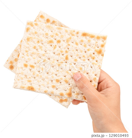 Hand holding traditional matzo crackers, a symbolic food in Jewish culture, isolated on white background 129010493