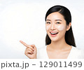 Radiant Asian Woman with Face Cream Smiles and Points to Blank Copy Space. 129011499