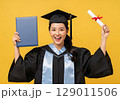 Triumphant Graduates Joyful Moment Holding Diploma and Certificate on Vibrant Yellow. 129011506