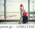 Wanderlust PinkHaired Woman with Luggage Gazing from Airport Window. 129011508