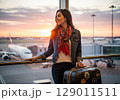 Anticipating Adventure Stylish Woman at Airport Window During Golden Sunset. 129011511