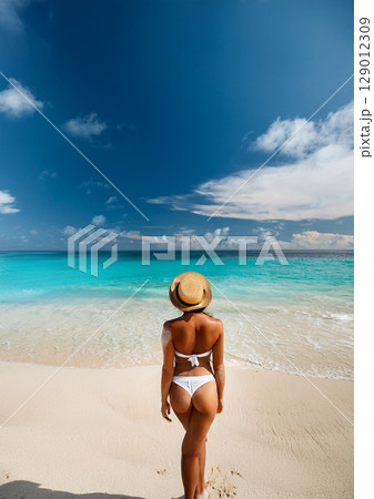 白い砂浜のビーチを歩く女性 129012309