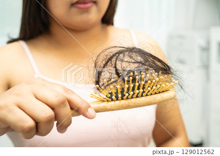 Asian woman have problem with long hair loss attach to comb brush. 129012562
