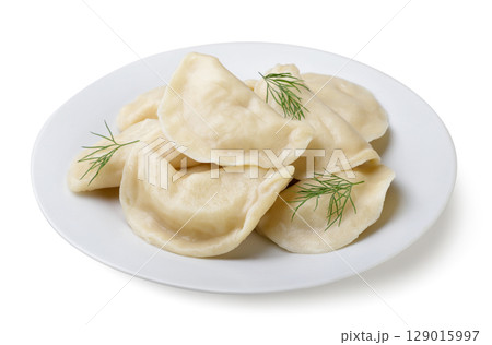 Boiled dumplings with dill leaves in a plate on a white background. Isolated 129015997