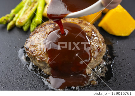 鉄板で焼いたハンバーグにデミグラスソースをかける瞬間 鉄板で焼いたハンバーグにデミグラスソースをかける瞬間 129016761