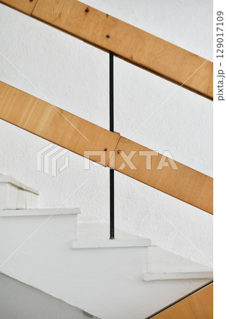 A flight of stairs with marble steps. Whitewashed walls and wooden staircase railings. The staircase of an old building. 129017109