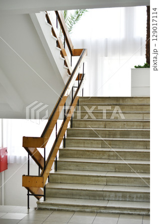 A flight of stairs with marble steps. Whitewashed walls and wooden staircase railings. The staircase of an old building. 129017114