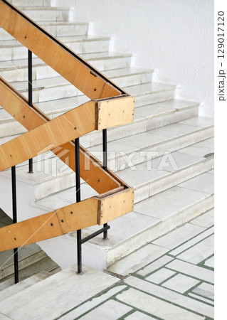 A flight of stairs with marble steps. Whitewashed walls and wooden staircase railings. The staircase of an old building. 129017120