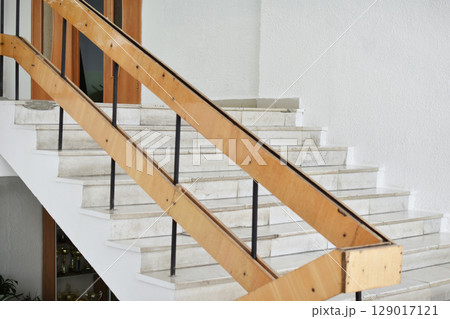 A flight of stairs with marble steps. Whitewashed walls and wooden staircase railings. The staircase of an old building. A flight of stairs with marble steps. Whitewashed walls and wooden staircase railings. The staircase of an old building. 129017121