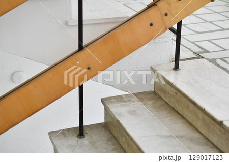 A flight of stairs with marble steps. Whitewashed walls and wooden staircase railings. The staircase of an old building. A flight of stairs with marble steps. Whitewashed walls and wooden staircase railings. The staircase of an old building. 129017123