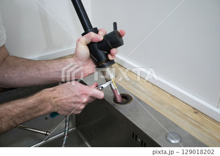 Repairman fixing kitchen faucet close up 129018202