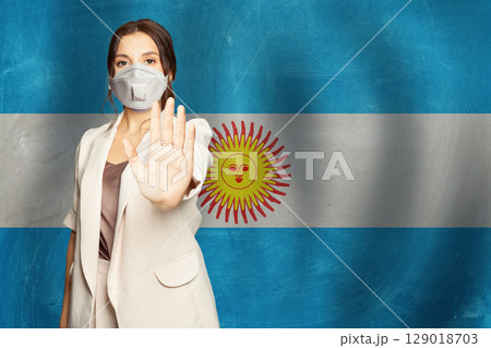 Confident woman in medical mask showing stop gesture open palm hand  129018703