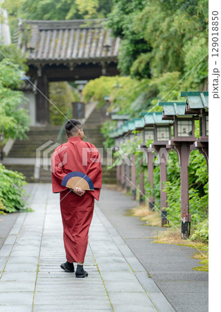 赤い着物を着て参道を歩く若い男性。京都, 日本 129018850
