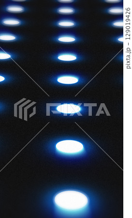 Blue illuminated circles in a grid pattern glowing over a dark surface, creating a futuristic LED look Blue illuminated circles in a grid pattern glowing over a dark surface, creating a futuristic LED look 129019426