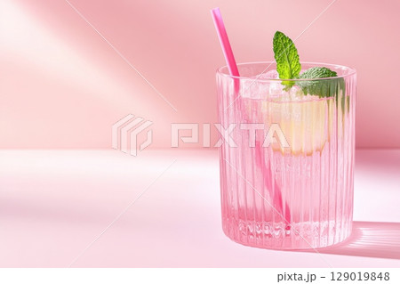 Refreshing mint lemonade in a pink glass with pastel straw and mint leaves served on a soft, pastel background 129019848