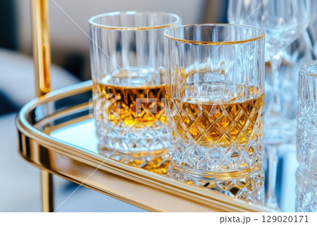 Elegant golden bar cart adorned with crystal decanters and fine spirits set in a luxurious living space 129020171