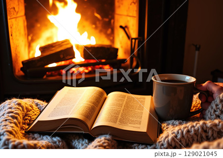 Cozy scene with book and coffee by fireplace. 129021045