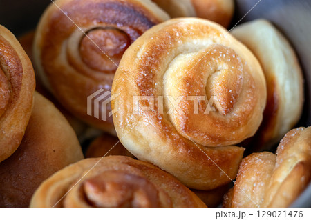 Freshly baked appetizing cinnamon and sugar rolls in close-up Freshly baked appetizing cinnamon and sugar rolls in close-up 129021476
