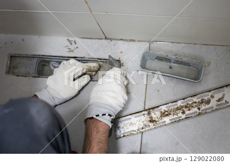 Top view of messy sewer hole, bathroom drain and worker hands 129022080