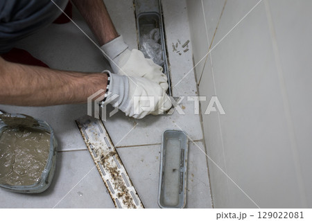 Bathroom drain on floor. Professional worker repairing sewer Bathroom drain on floor. Professional worker repairing sewer 129022081