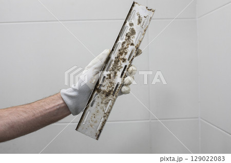 Stained Mold Drain in Plumber Hand 129022083
