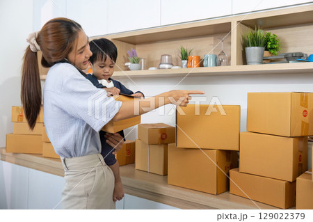 Mother and Child Engaging in Home Business with Shipping Boxes 129022379