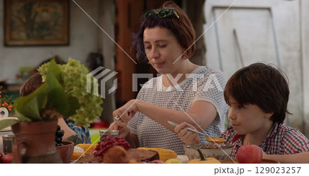 Family gathers around a beautifully set table for Thanksgiving, sharing laughter and stories while enjoying traditional dishes that celebrate gratitude and connection. 129023257