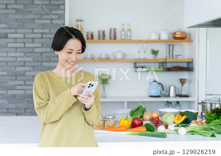 キッチンでスマホを使うミドルの女性 キッチンでスマホを使うミドルの女性 129026259