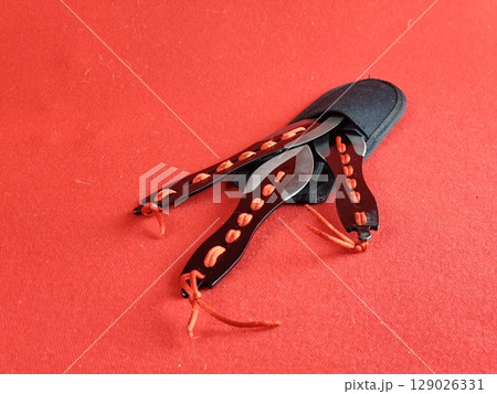 A set of several throwing knives in a case for combat training and sport throwing on red background. 129026331