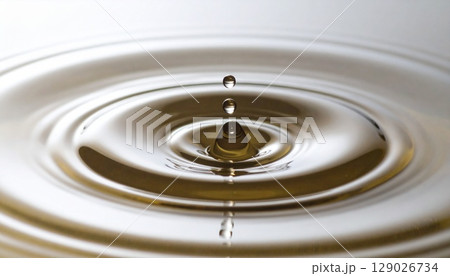 黄金の美容液や化粧水イメージ　水面に滴が落ちる瞬間と波紋の美しいクローズアップ背景 129026734