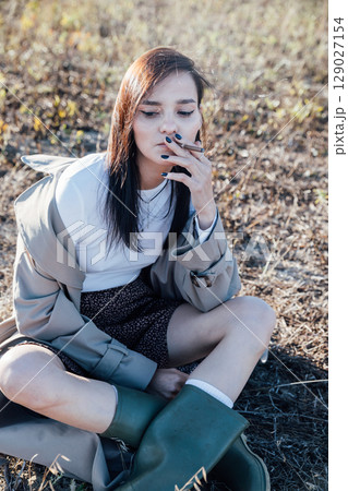 woman sitting on the ground and smoking 129027154