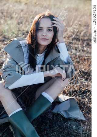 Beautiful brunette woman in sitting on an autumn field Beautiful brunette woman in sitting on an autumn field 129027158