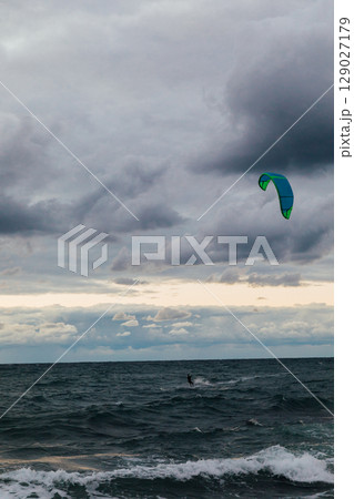 Kite surfing athlete riding waves in storm 129027179