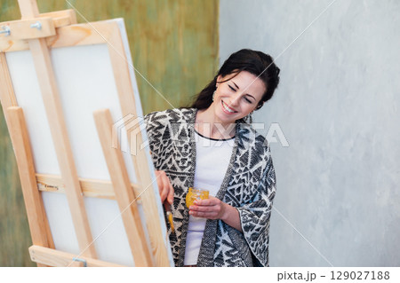 artist paints a picture on easel with brushes artist paints a picture on easel with brushes 129027188