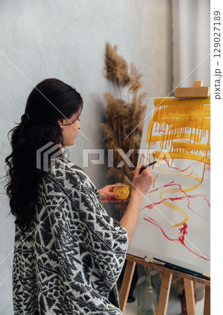 artist paints a picture on easel with brushes artist paints a picture on easel with brushes 129027189