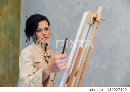 artist paints a picture on easel with brushes artist paints a picture on easel with brushes 129027190