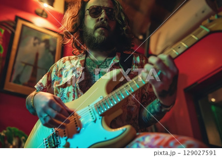 Musician with long hair plays an electric guitar in a recording studio, fully immersed in creating rock music. The atmosphere is filled with captivating sounds 129027591