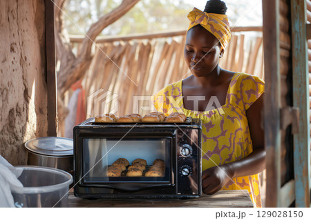 African baker woman is taking bread out of the oven in a rural house in Namibia African baker woman is taking bread out of the oven in a rural house in Namibia 129028150