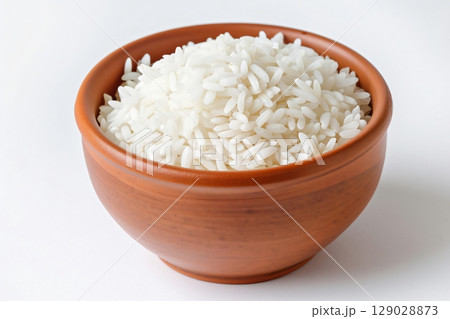 Fluffy white rice in a clay bowl, steamed to perfection, on a white background. Ideal for food projects 129028873