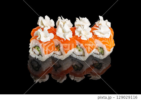 Fresh sushi rolls topped with salmon slices and delicate cream rosettes are beautifully arranged on a glossy black surface Fresh sushi rolls topped with salmon slices and delicate cream rosettes are beautifully arranged on a glossy black surface 129029116