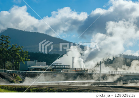Geothermal power plant releasing plumes of steam into the atmosphere, showcasing renewable energy generation 129029218
