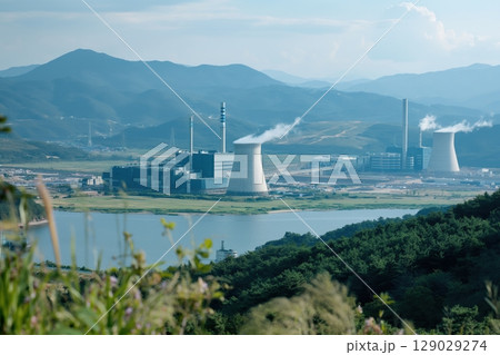 Nuclear power plant is generating electricity near a lake and mountains on a sunny day 129029274