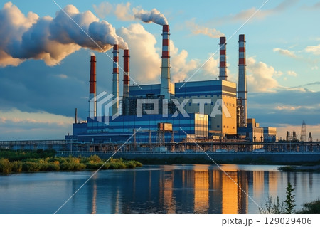 Sun setting over coal power station emitting pollution, impacting environment with harmful emissions, highlighting fossil fuel use and climate change 129029406